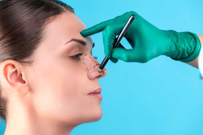 surgeon examining female nose